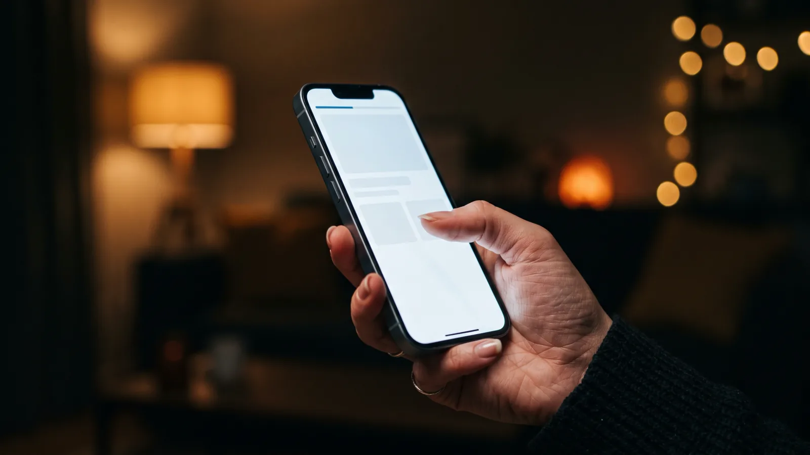 Mão segurando um celular à noite logo depois de tocar em um link, com a página ainda carregando na tela